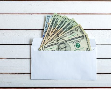 CashShareholder Letters in an envelope, the denomination on a table from white wooden boards.