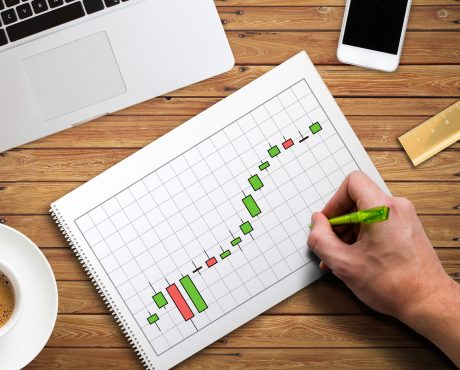 hand writing a candlestick chart on a college block