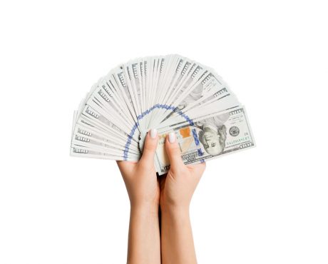 Female hands holding a fan of dollar banknotes on isolated background. Succes and investment concept