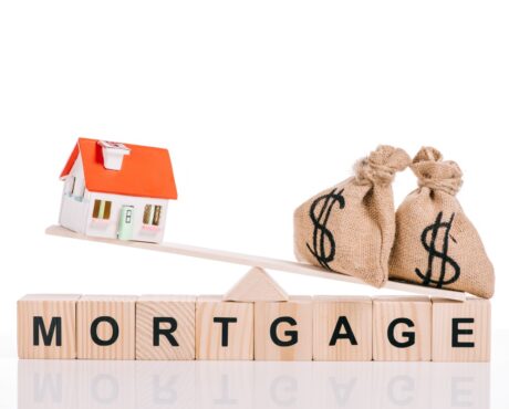 wooden blocks with mortgage lettering and scales with moneybags and house model isolated on white